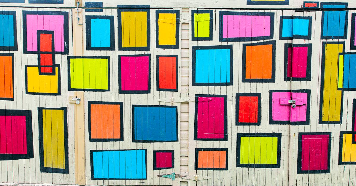 Mural geométrico pintado con plantillas sobre un muro de hormigón claro